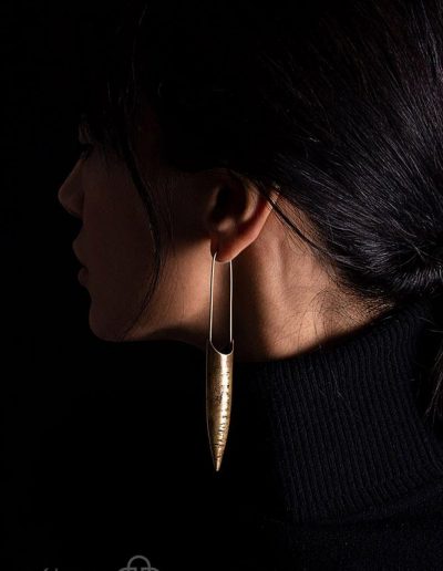 گوشواره دست ساز برنجی آویزه، آویخته به گوش مدل در زمینه سیاه